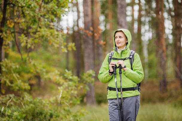 woman with hiking equipment walking in forest - Zdjęcie, obraz