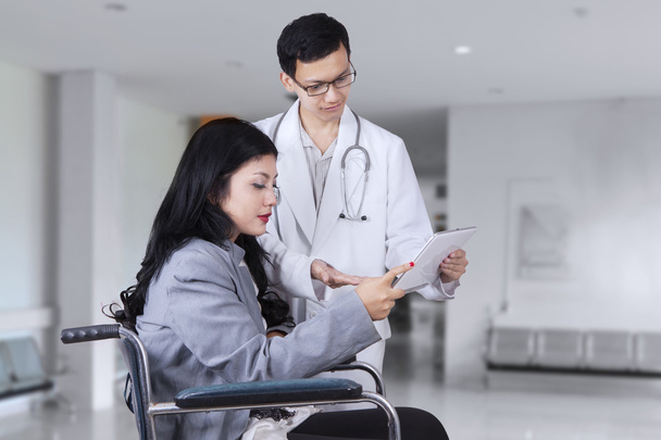 Médico mostrando relatório médico em paciente com deficiência
 - Foto, Imagem