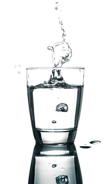 наливая воду на стакан на белом фоне
 - Фото, изображение