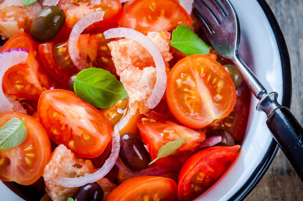 Panzanella: Italiaanse salade met tomaten, ciabatta, olijven, rode ui en basilicum close-up - Foto, afbeelding