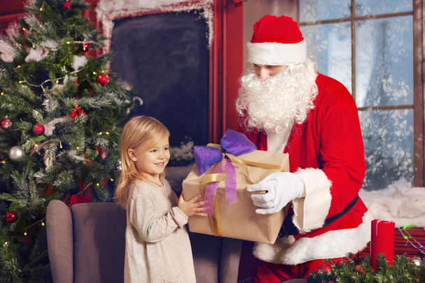 улыбающаяся маленькая девочка с Санта Клаусом и подарками
 - Фото, изображение