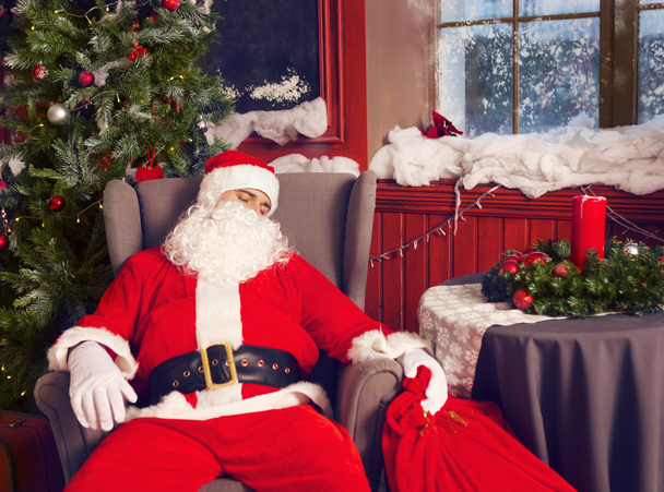 Foto de Papá Noel feliz con gran bolsa de regalos durmiendo
 - Foto, Imagen