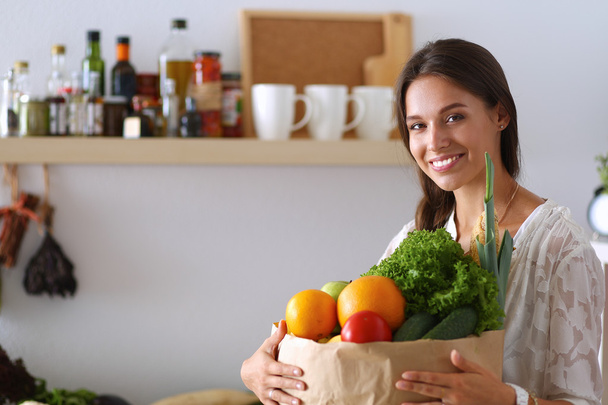 Молода жінка тримає продуктовий сумку з овочами
 - Фото, зображення