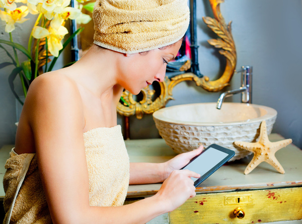 Female in bathroomreading ebook tablet - 写真・画像