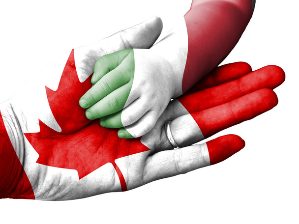 Volwassen mens bezit is van de hand van een baby met Canada en Italië vlaggen bedekt. Geïsoleerd op wit - Foto, afbeelding