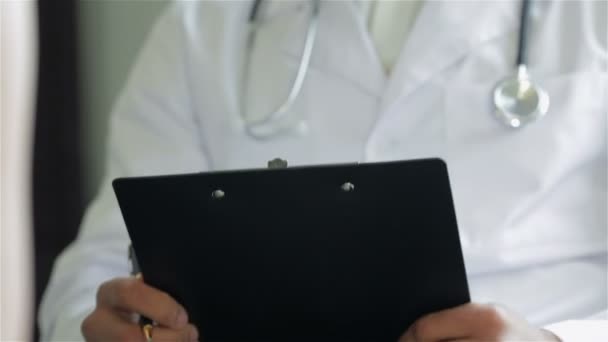 Lekarz posiada uchwyt na papier i pisze - Materiał filmowy, wideo