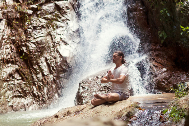 Relaxed guy sitting near the waterfall. - Foto, afbeelding