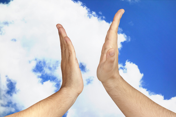 Mãos dando um High Five ao ar livre contra nuvens azuis do céu
 - Foto, Imagem