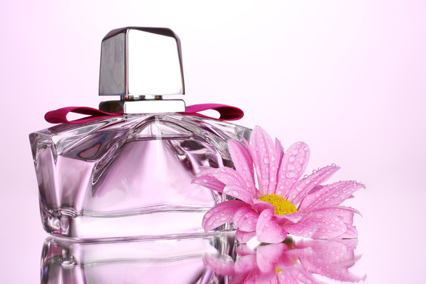 Women's perfume in beautiful bottle and flower on pink background - 写真・画像