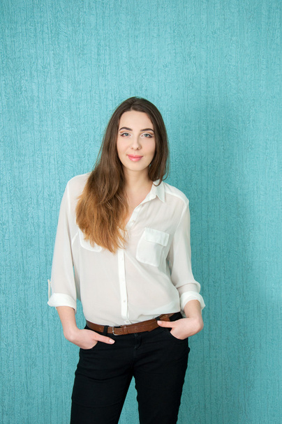Young woman in white blouse near blue wall - Zdjęcie, obraz
