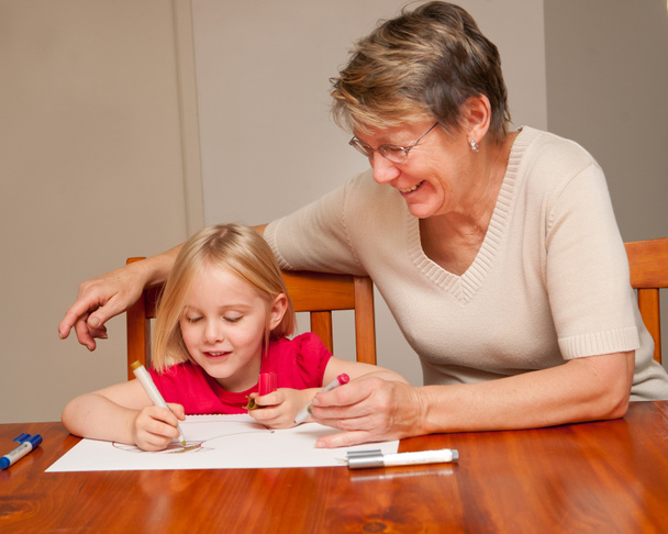 A little girl drawing with her carer - Zdjęcie, obraz