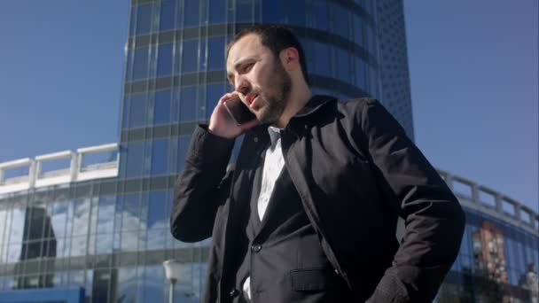 Man talking on the phone and looking on his watch outdoors - Video, Çekim