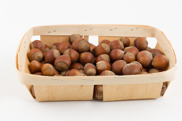 wooden container is filled with hazelnut on a white background - Photo, Image