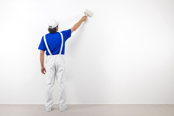 Painter with paintbrush on white wall - Fotoğraf, Görsel