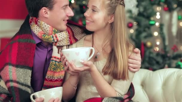 Fiatal pár szerelmes férfi és csinos lány visel pulóver és sál otthon - Felvétel, videó