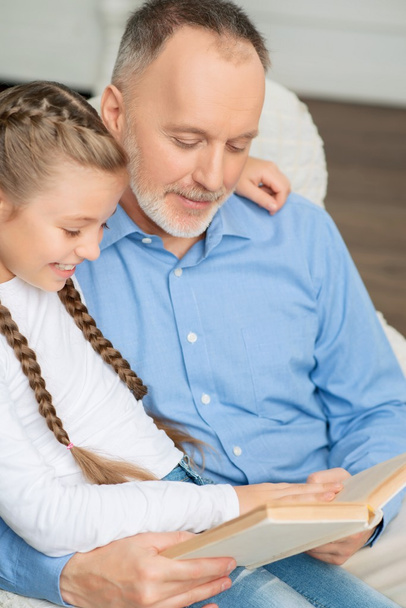 Grandfather with little girl reading book - Foto, imagen