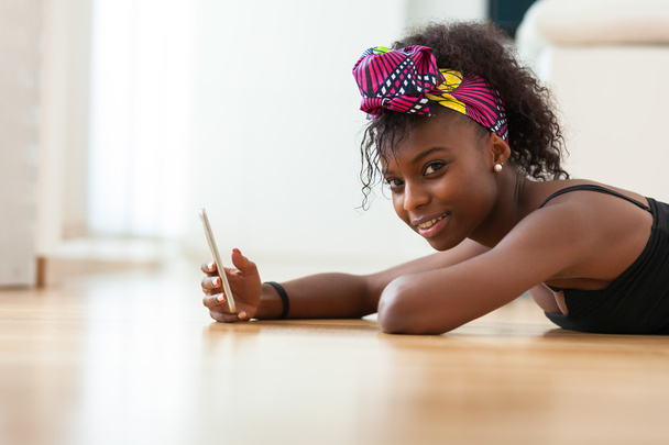 Afrikkalainen amerikkalainen nainen lähettää tekstiviestin matkapuhelimeen
 - Valokuva, kuva