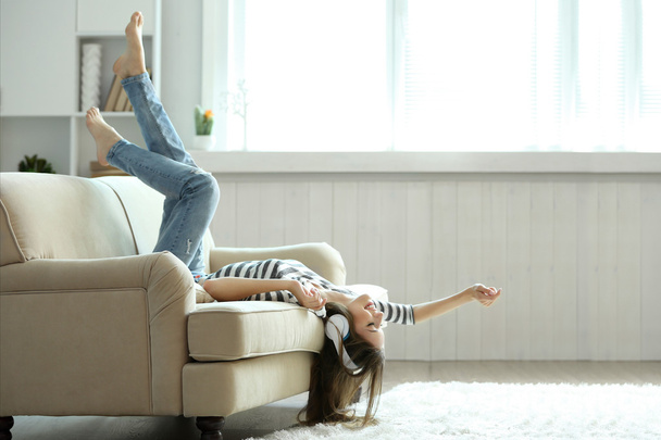 Woman listening music in headphones while lying on sofa in room - Фото, зображення