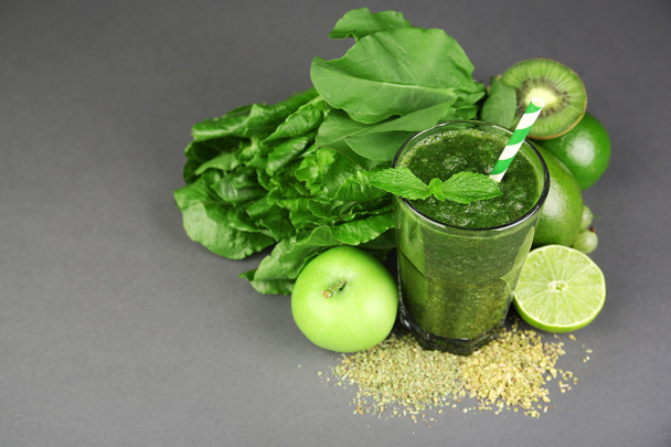 Green healthy juice with fruits and herbs on gray background - 写真・画像