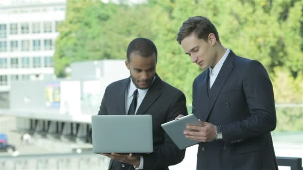 Kaksi liikemiestä, joilla on tabletti ja kannettava tietokone kädessä
 - Materiaali, video