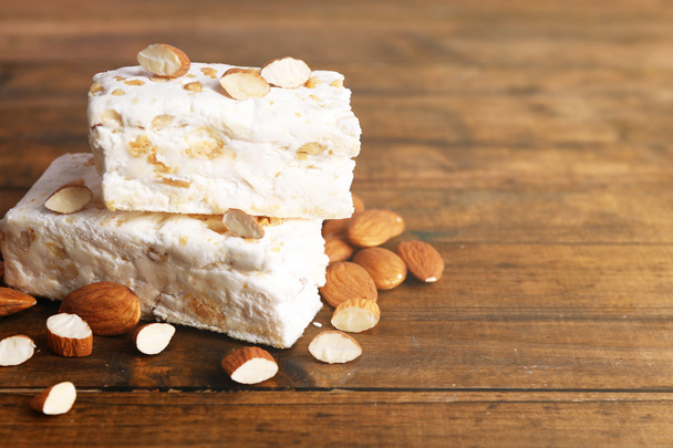 Sweet nougat with almonds on wooden background - Fotó, kép