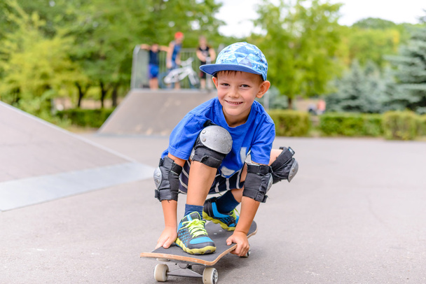 Menino pequeno em seu skate sorrindo para a câmera
 - Foto, Imagem