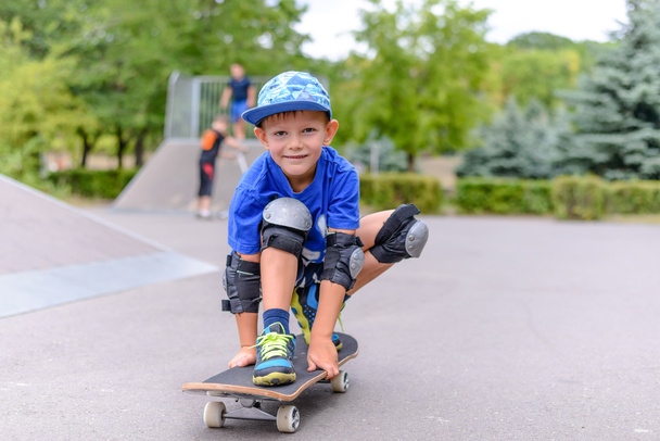 Menino pequeno em seu skate sorrindo para a câmera
 - Foto, Imagem