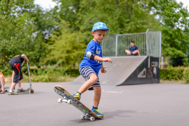 Mały chłopiec bawi się jego skateboard - Zdjęcie, obraz