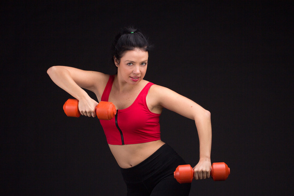 Brutal athletic woman pumping up muscules with dumbbells - Fotó, kép
