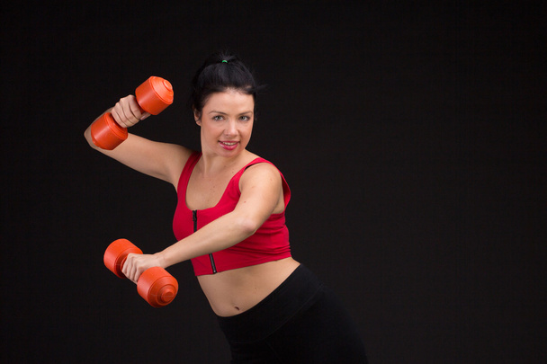 Brutal athletic woman pumping up muscules with dumbbells - Fotó, kép
