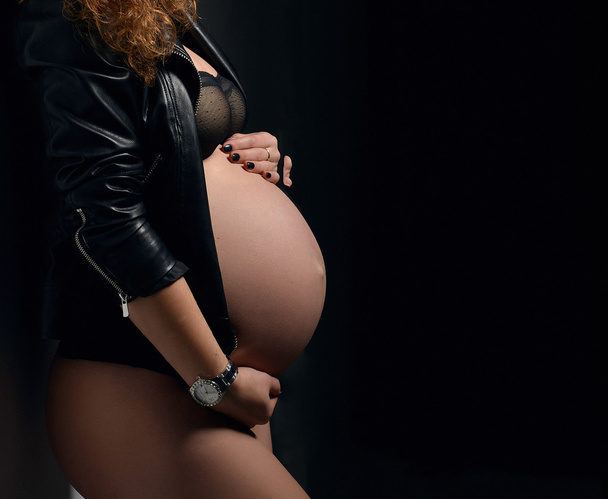 Pregnant woman abdomen on black background - Foto, Imagen
