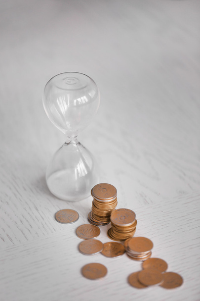 Hourglass with coins on table close-up - 写真・画像
