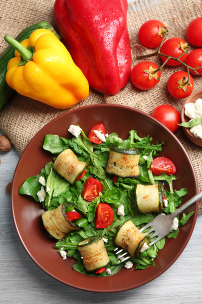 Salad with arugula and zucchini rolls on plate, on table background - Foto, Imagen