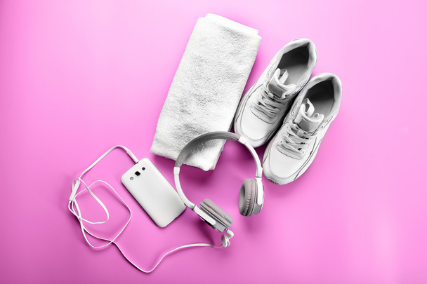 Sport shoes, towel and headphones on pink background - Fotó, kép