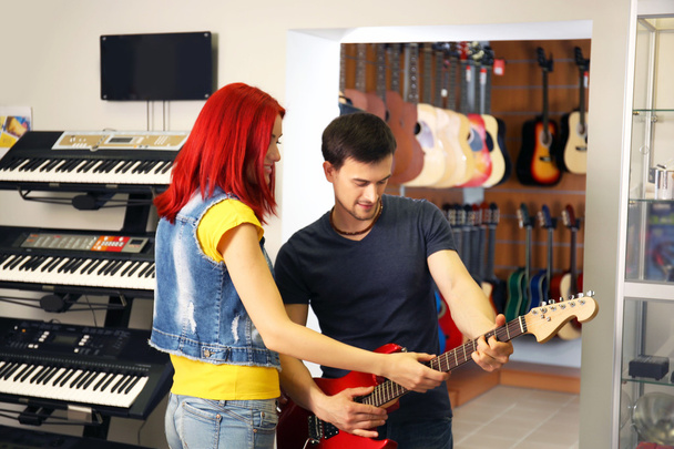 Beautiful young couple in music store - Foto, afbeelding