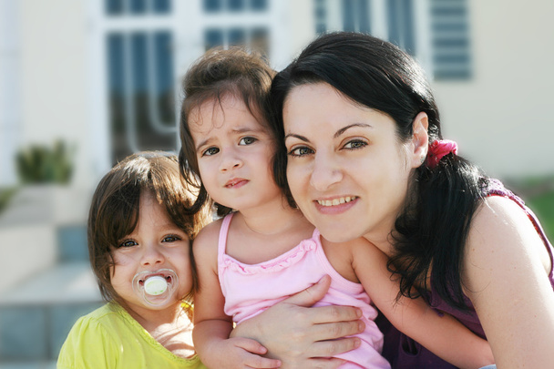 Портрет матері та дочок на відкритому повітрі перед їхнім будинком
 - Фото, зображення