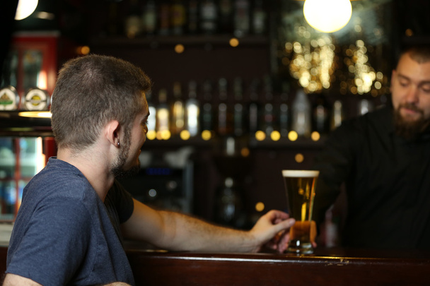 Young man drinking beer in bar - Valokuva, kuva