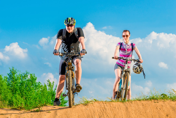 пара молодих велосипедистів на пагорбі проти неба
 - Фото, зображення