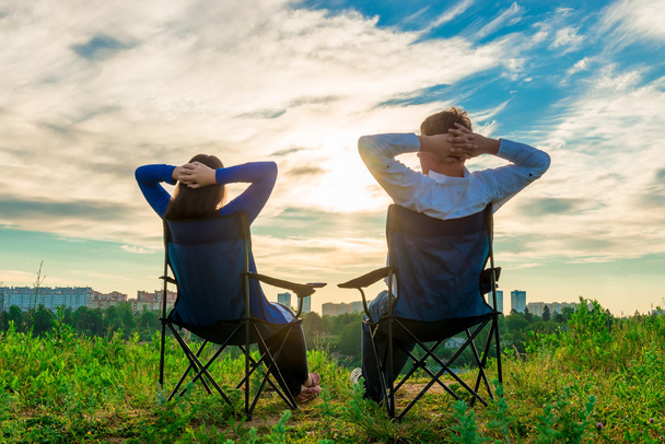 man en vrouw in stoelen zitten en genieten van de zonsopgang op de - Foto, afbeelding