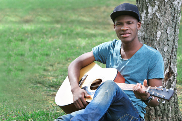  man with guitar sitting in park - Foto, imagen