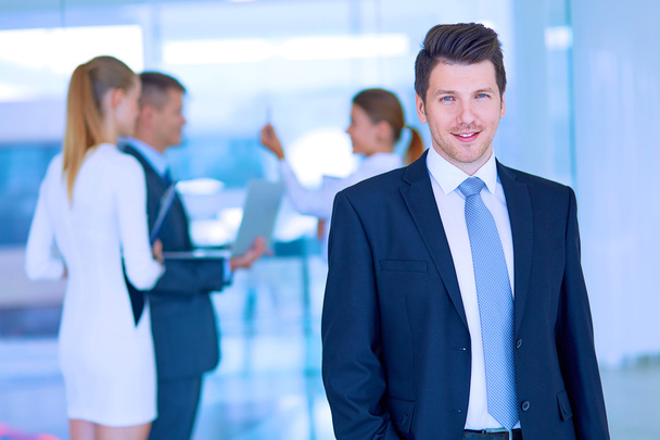 Portrait of young businessman in office with colleagues in the background - Foto, Bild