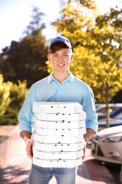 Pizza delivery boy holding boxes with pizza, outdoors - Фото, зображення