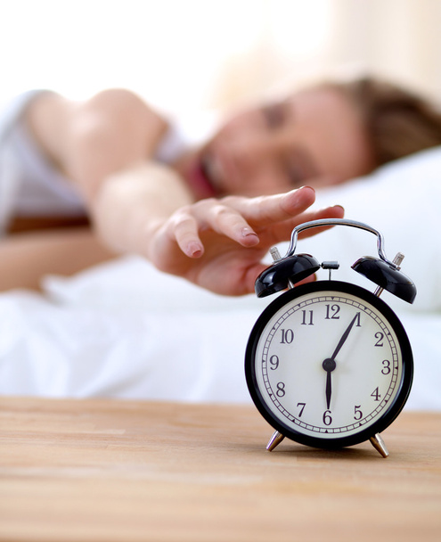 Young sleeping woman and alarm clock in bedroom at home - Valokuva, kuva