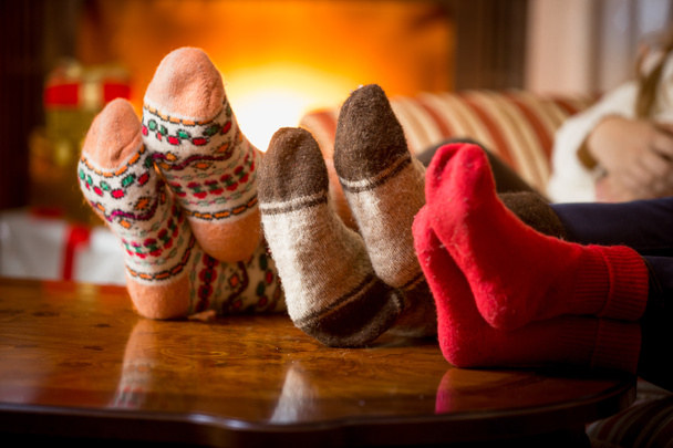 暖炉のそばでウールの靴下で家族の足のクローズ アップ - 写真・画像