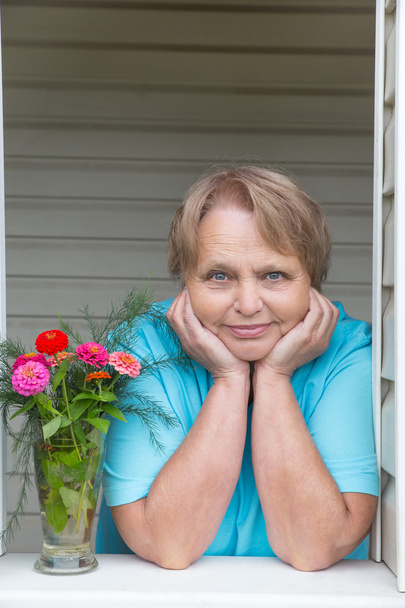 Спокійна і мирна пенсіонерка біля вікна з квітами
 - Фото, зображення