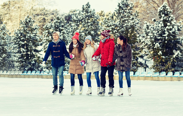happy friends ice skating on rink outdoors - Foto, imagen