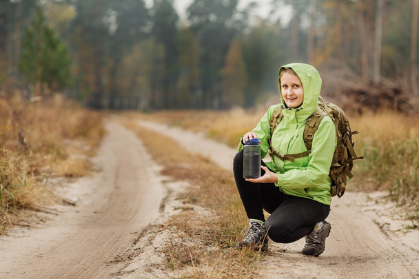 young woman drinking water with backpack at forest valley - 写真・画像