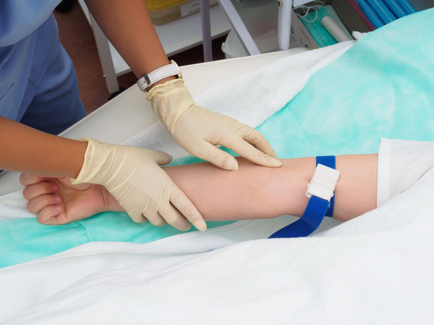 Arzt entnimmt dem Arm einer Patientin Blut zur Untersuchung - Foto, Bild