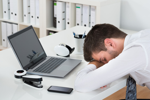 Biznesmen z laptopa do spania na biurko - Zdjęcie, obraz