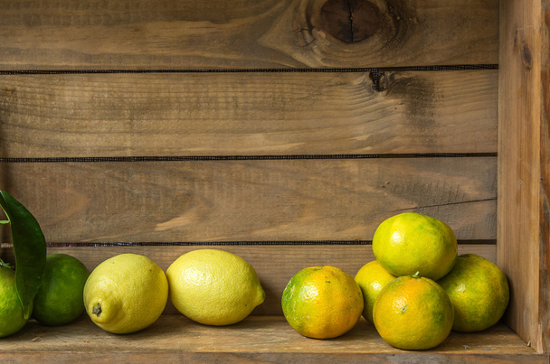 Ripe sweet lemon and tangerine with leaves on wooden board - 写真・画像